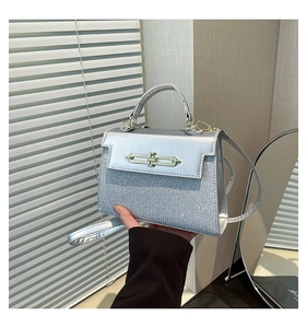 Detail of silver glittery square crossbody bag with metallic latch and slim shoulder strap