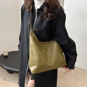 Olive green large PU leather hobo bag worn by model over a black stylish trench coat