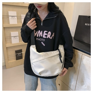 Detailed shot of a white crescent crossbody bag showing its nylon texture and capacity