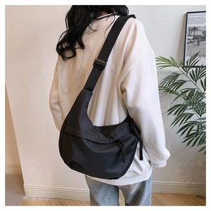 Side view of a large black crescent crossbody bag made of durable nylon on a model