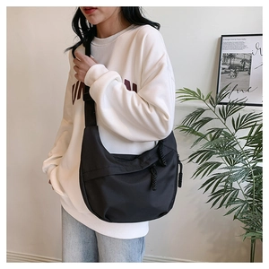 Detail of a black half-moon crossbody bag in durable nylon with adjustable shoulder strap