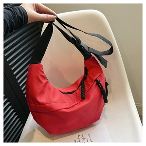 Detail of red crescent nylon crossbody bag featuring black adjustable wide shoulder strap