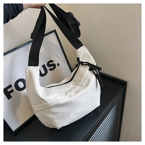 Detail of white crescent shoulder bag with black adjustable strap and buckle closure