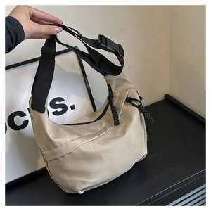 Detail of khaki crescent crossbody bag showing nylon texture and braided rope zipper pull