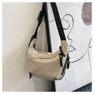 Detail view of khaki half-moon crossbody bag with wide black strap and buckle