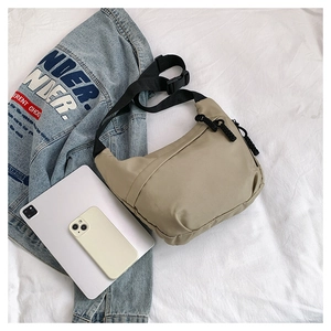 Detail of khaki nylon crossbody bag with adjustable strap and tablet for size comparison