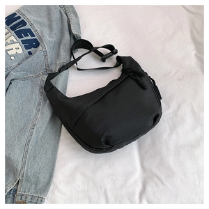 Detail view of black crescent shoulder bag with nylon texture and adjustable strap