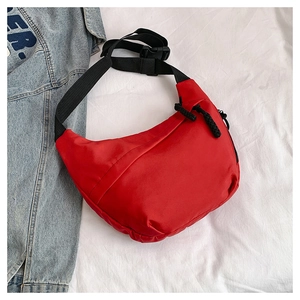 Close-up of a red crescent-shaped sling bag with adjustable strap and buckle closure