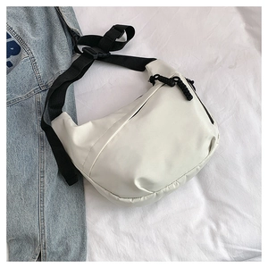 Detail of white crescent crossbody bag with black nylon strap on blue denim background