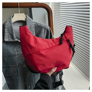 Detail of red crescent shoulder bag with adjustable strap and durable nylon texture