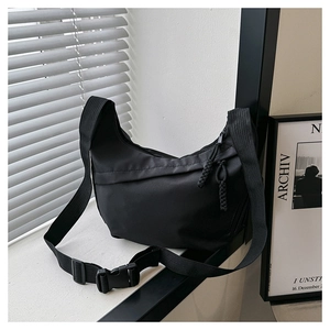 Detail of black nylon crescent bag with wide shoulder strap and woven zipper puller