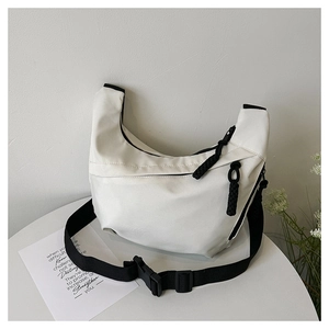 Detailed view of white hobo bag with black adjustable strap and buckle on white table