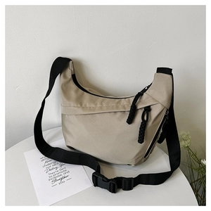 Detail of khaki nylon crescent bag featuring black adjustable strap and woven zipper pull