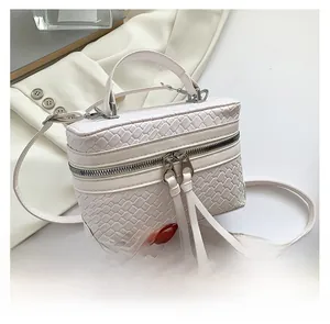 Détail du sac seau blanc tressé avec double fermeture éclair et longs pompons à franges