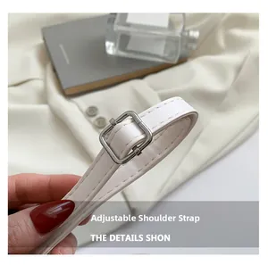 Détail de la bandoulière réglable en similicuir blanc avec une boucle en métal argenté