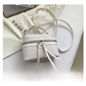 Détail du sac boîte tressé crème avec deux fermetures éclair à pompons en cuir