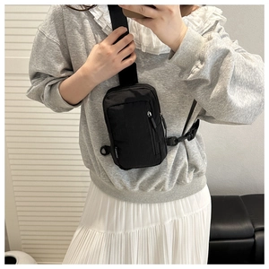 Detailed view of black nylon cross body bag with adjustable strap and zip closure