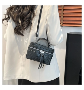Detail of black woven texture handbag with long tassel zipper and detachable shoulder strap
