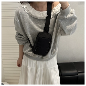 Detail of black nylon crossbody chest bag with adjustable strap and fashion label