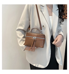 Brown woven texture box bag with long tassels shown on shoulder with beige blazer