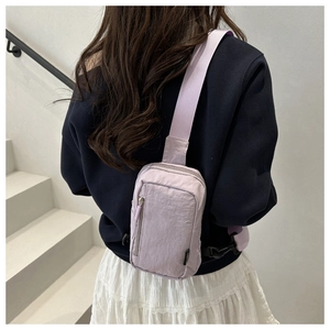 Detail of light purple nylon crossbody bag with zipper pockets and adjustable strap
