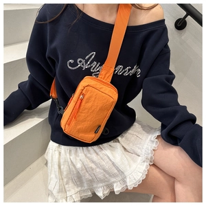 Detail der orangefarbenen Brusttasche aus Nylon mit Doppelreißverschluss und Tragegurt
