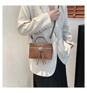 Detail of brown woven faux leather bucket bag featuring elegant long fringe zipper pulls