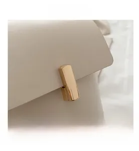 Détails de la texture du cuir crème de qualité et boucle dorée sur le sac à bandoulière