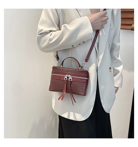 Detail of burgundy woven texture on small crossbody bag with double tassels and zip