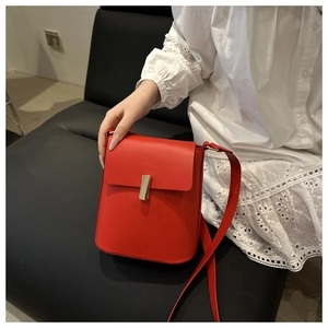 Dettaglio borsa a tracolla in pelle rossa con fibbia magnetica rettangolare dorata elegante