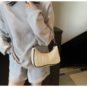 Détail du sac hobo en paille tissée avec bordure en cuir noir et chaîne dorée