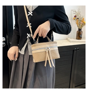 Detail of beige woven square bag with silver hardware and tassels in a cafe setting