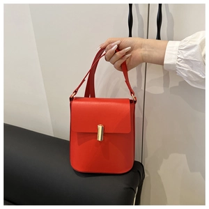 Dettaglio della borsa a tracolla in pelle rossa con fibbia cilindrica in metallo dorato