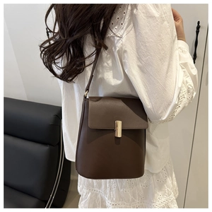 Dettaglio della borsa a secchiello in pelle marrone con elegante chiusura dorata