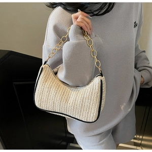Détail d'un sac baguette en paille avec bordure en cuir noir et poignée dorée