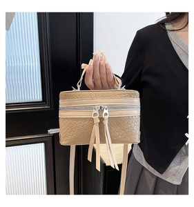 Detail of beige woven texture handbag with dual zippers and long fringe tassel pulls