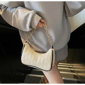 Détail du sac en paille tissée beige avec bordure en cuir noir et chaîne dorée