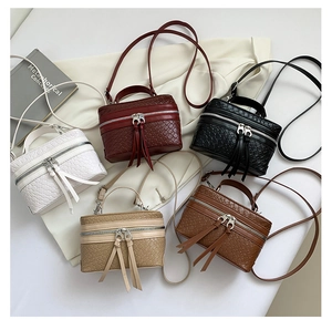 Detail of five woven box bags in various colors with long tassels and top handles