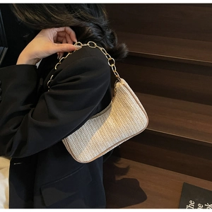 Détail du sac hobo en paille tressée avec bordure marron et chaîne dorée chic