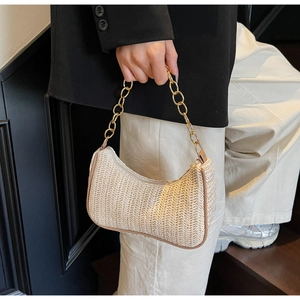 Détail du sac baguette en paille tressée beige avec chaîne dorée et bordure en cuir
