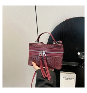 Détail d'un sac à main tissé bordeaux avec de longs glands en cuir et une poignée chic