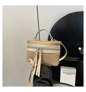 Détail du sac boîte beige structuré avec texture tissée et doubles zips métalliques