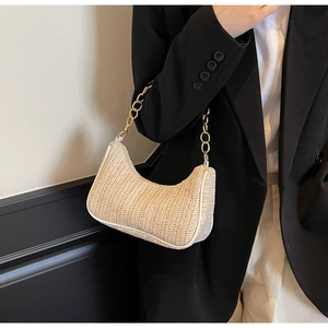 Détail du sac baguette en paille tressée avec chaîne en métal doré sur le mannequin