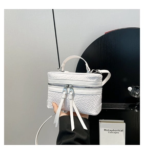 Détail d'un sac boîte blanc tressé avec poignée et double fermeture éclair