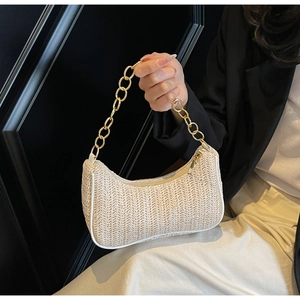 Gros plan détaillé du sac baguette en paille tressée avec texture beige et chaîne dorée