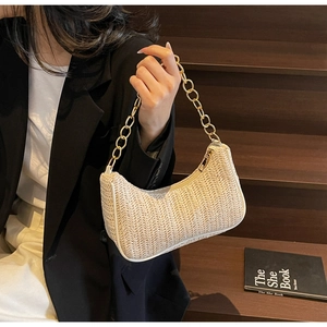 Détail du sac hobo en paille tressée avec bordure en cuir blanc et chaîne dorée chic