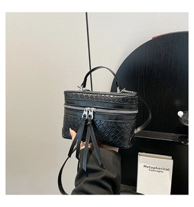 Détail du sac boîte noir tressé avec doubles glands et poignée supérieure élégante