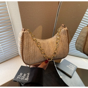 Détail du sac baguette tressé beige avec bordure marron et grosse chaîne dorée