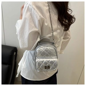 Detail eines silbernen gesteppten Mini-Rucksacks mit Kettenriemen und Metalldrehverschluss