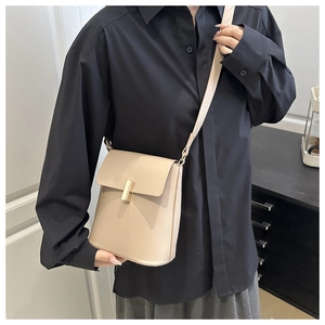 Vue latérale d'un sac bandoulière beige minimaliste avec fermoir doré sur modèle